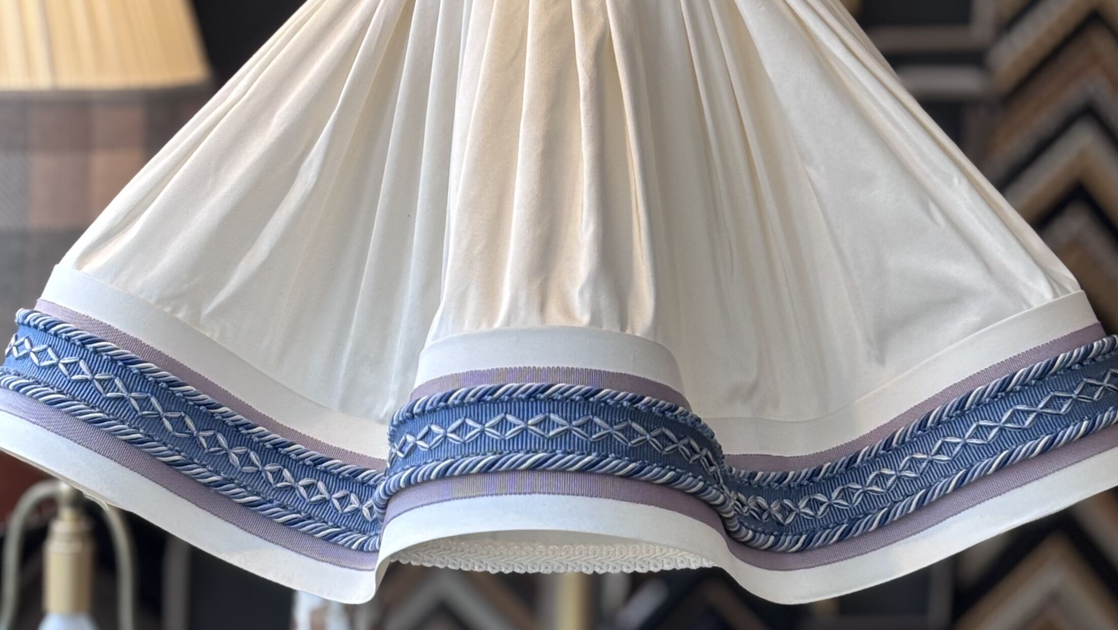 Abat-jour plissé ivoire terminé par un galon bleu, sur son pied de lampe