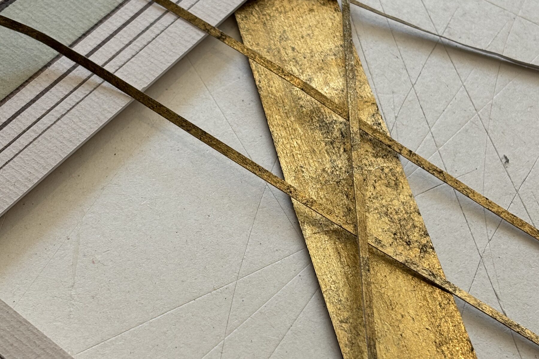 Filets à la feuille d'or posés sur un passe-partout tracé au crayon